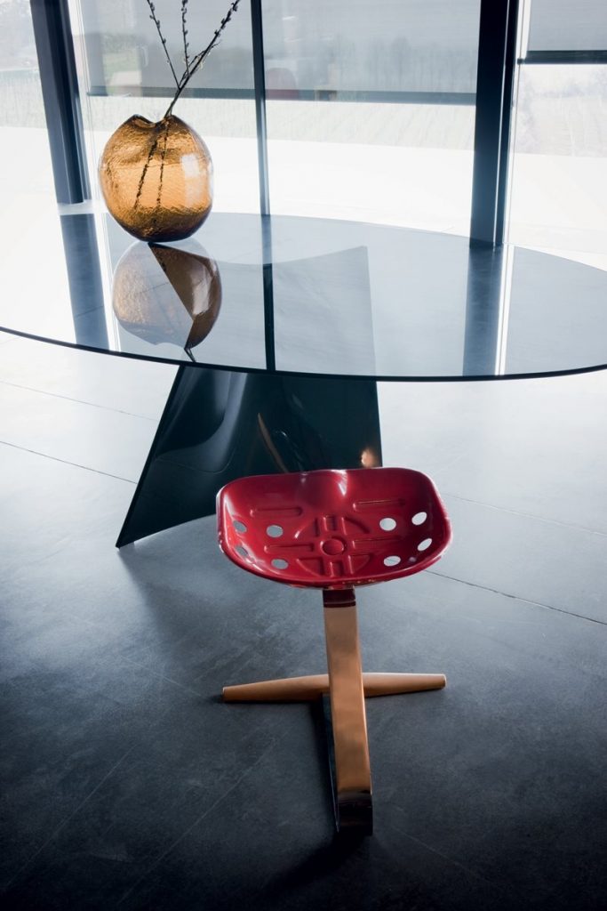 Mezzadro red stool with a unique design, featuring a red seat on a chrome base on a gray background.