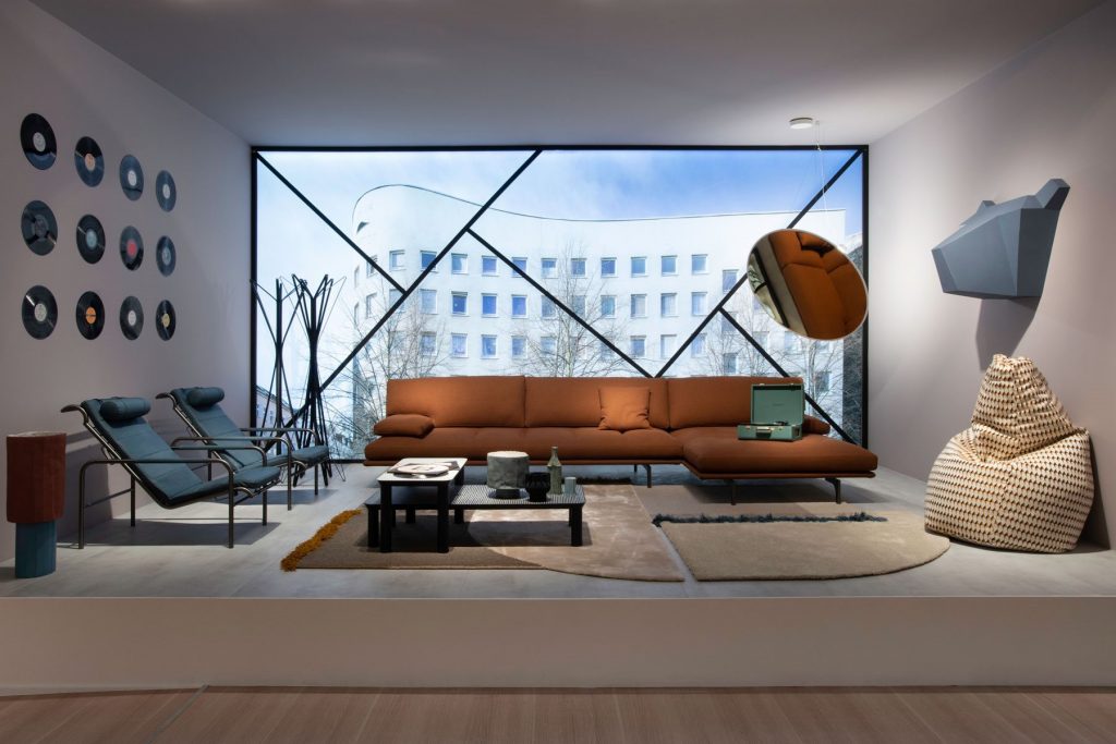 Red Milano+ sofa with armrest and backrest and a black metal frame in a living room.