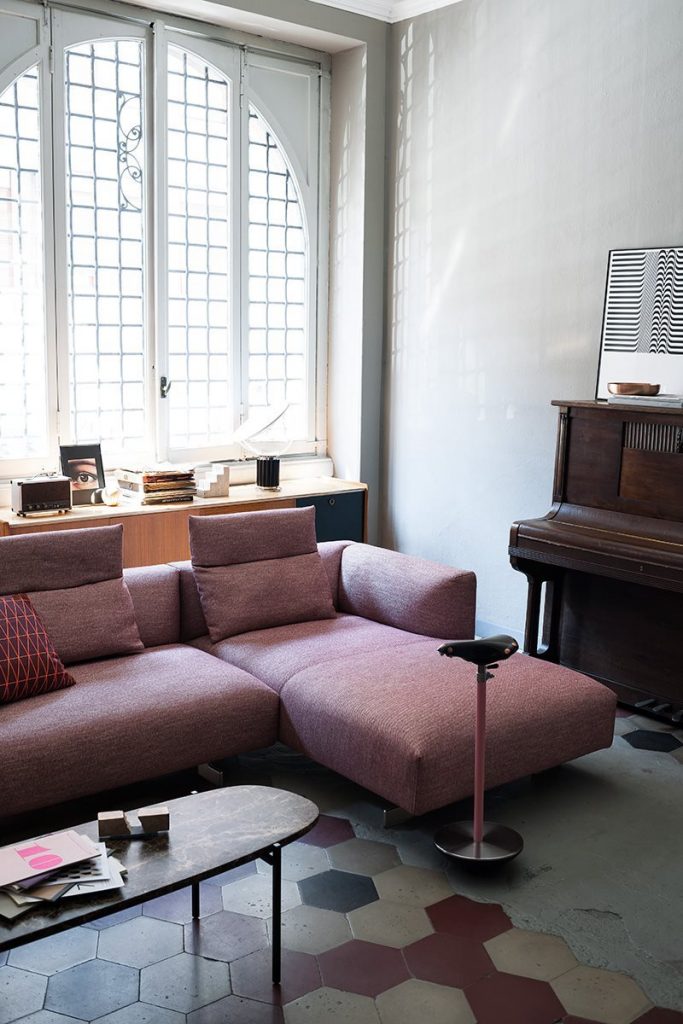 Sella stool with a unique design, featuring a black seat and a pink metal base in a living room.