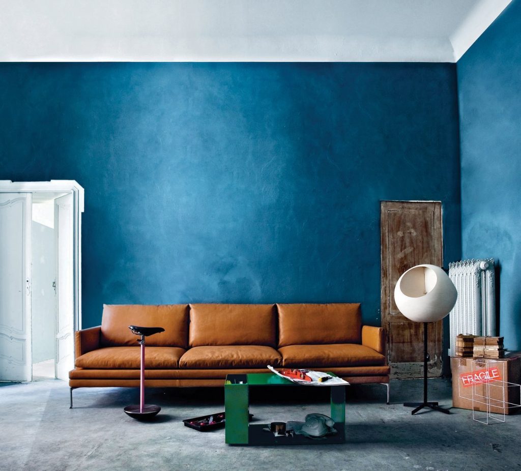 Sella stool with a unique design, featuring a black seat and a pink metal base in a living room.