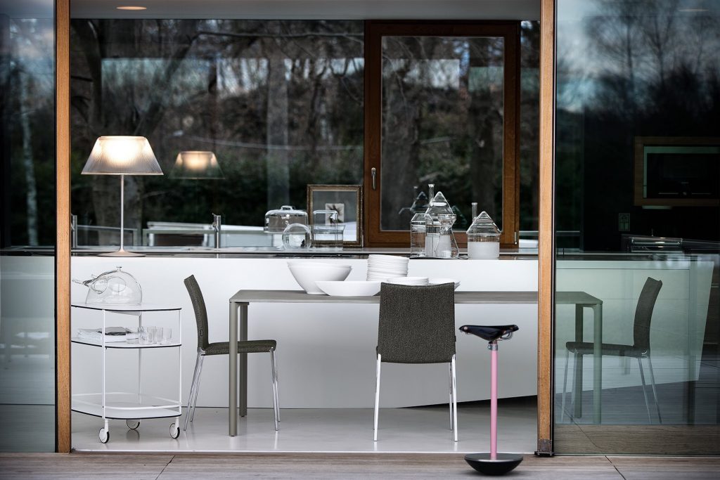 Sella stool with a unique design, featuring a black seat and a pink metal base in a living room.