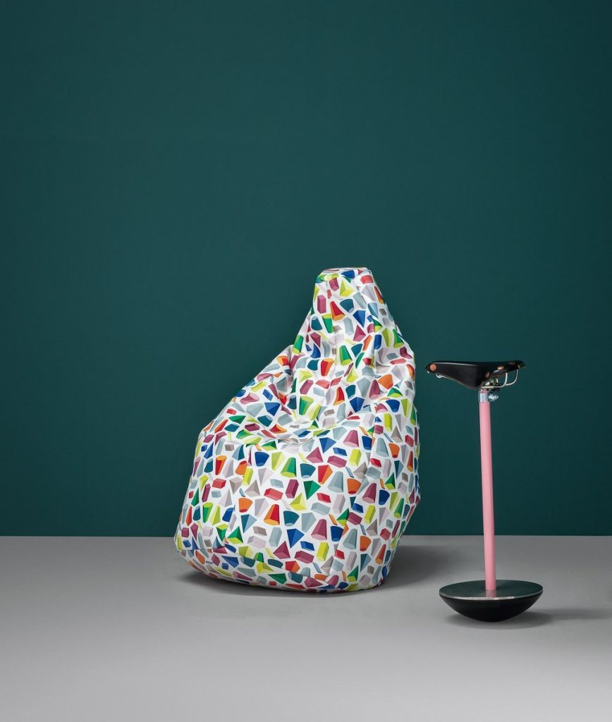 Sella stool with a unique design, featuring a black seat and a pink metal base in a living room.