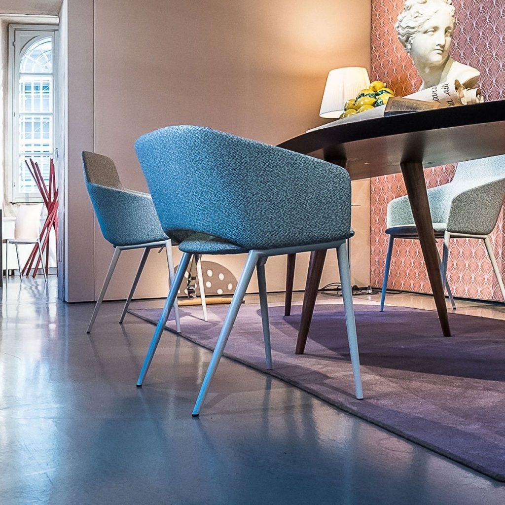 Three Tusa 2261/B chair with a curved backrest and seat upholstered in dark gray fabric in a dining room.