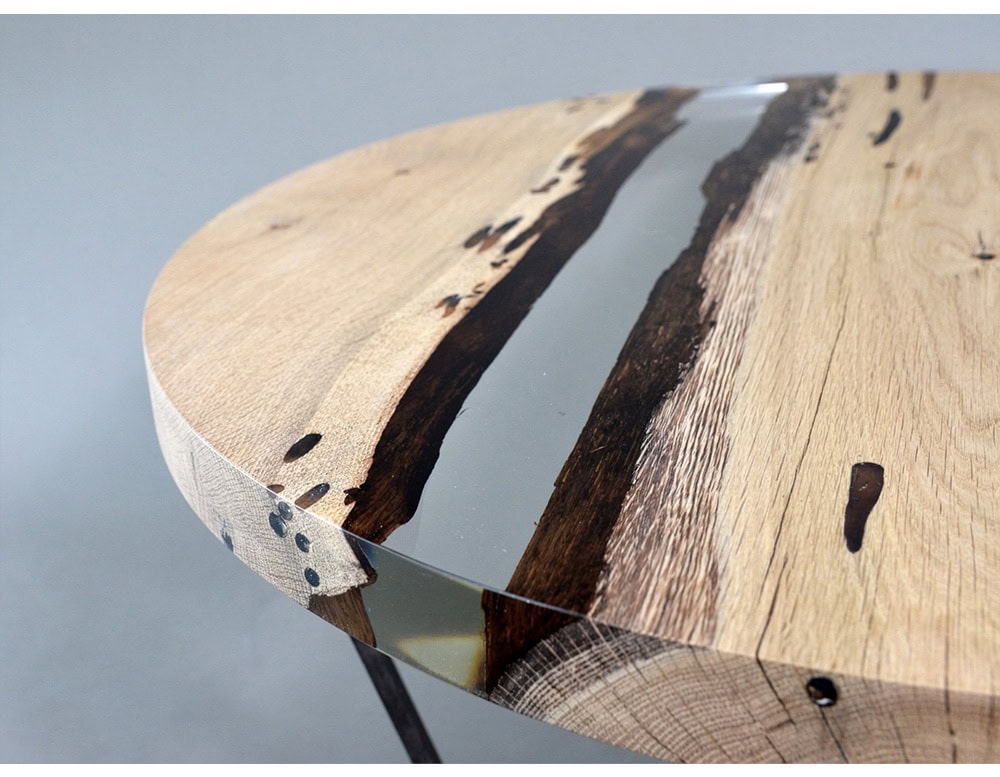 A striking round table combining natural wood planks with resin for a flowing river-like effect. The organic textures contrast with the polished surface, offering a refined yet earthy centerpiece.
