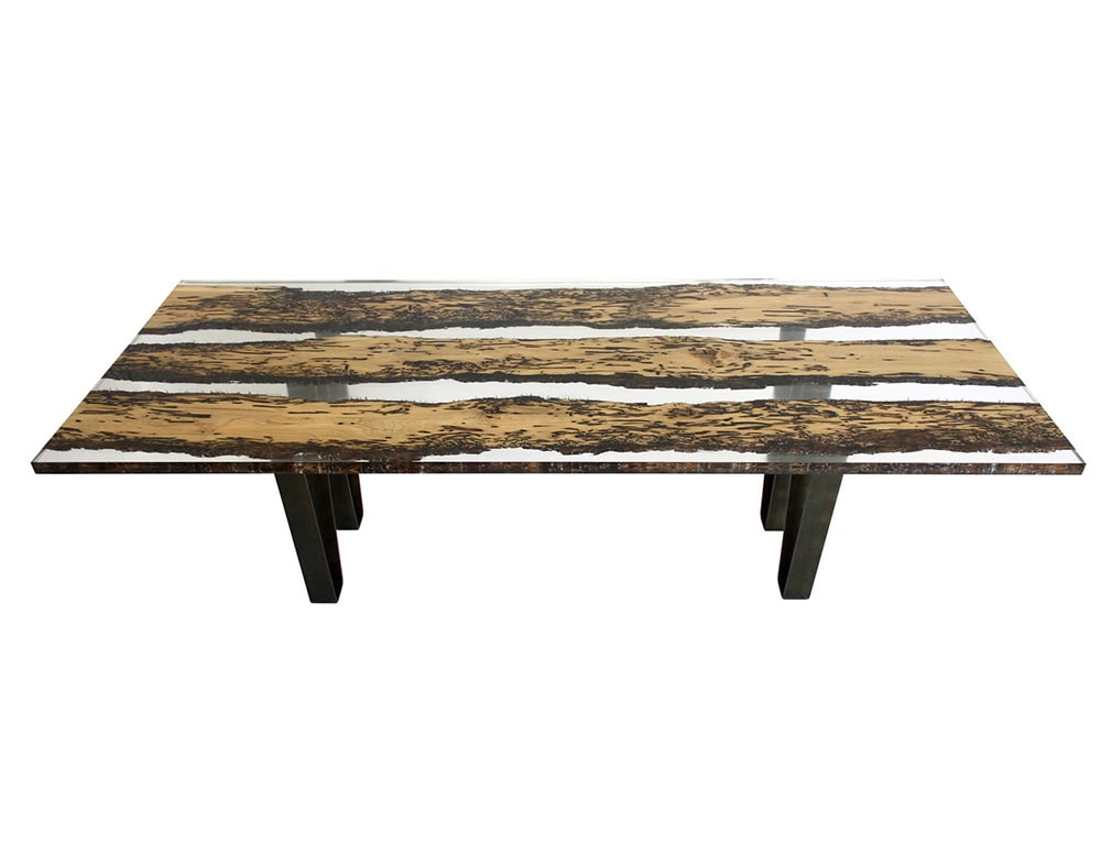 A striking rectangular table combining natural oak planks with transparent resin, showcasing organic textures and voids. Supported by sturdy geometric legs, it creates a bold yet refined centerpiece for dining or workspace settings.