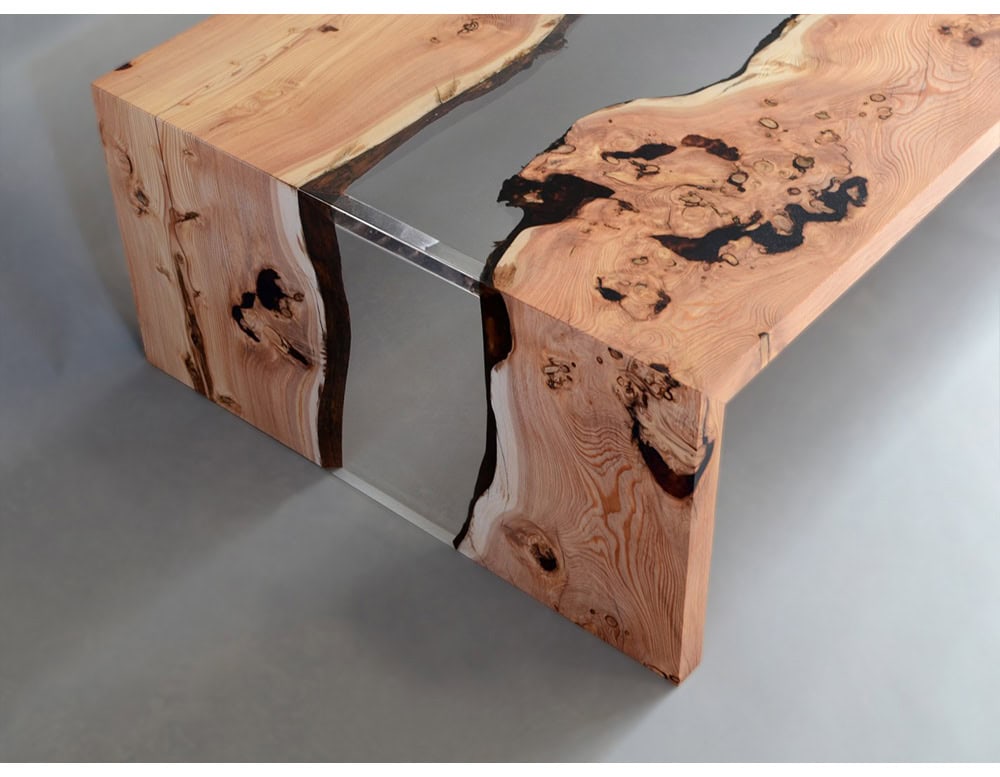 A modern coffee table merging raw wood edges with a clear resin river, creating depth and flow. Its natural textures and refined finish make it both functional and sculptural.