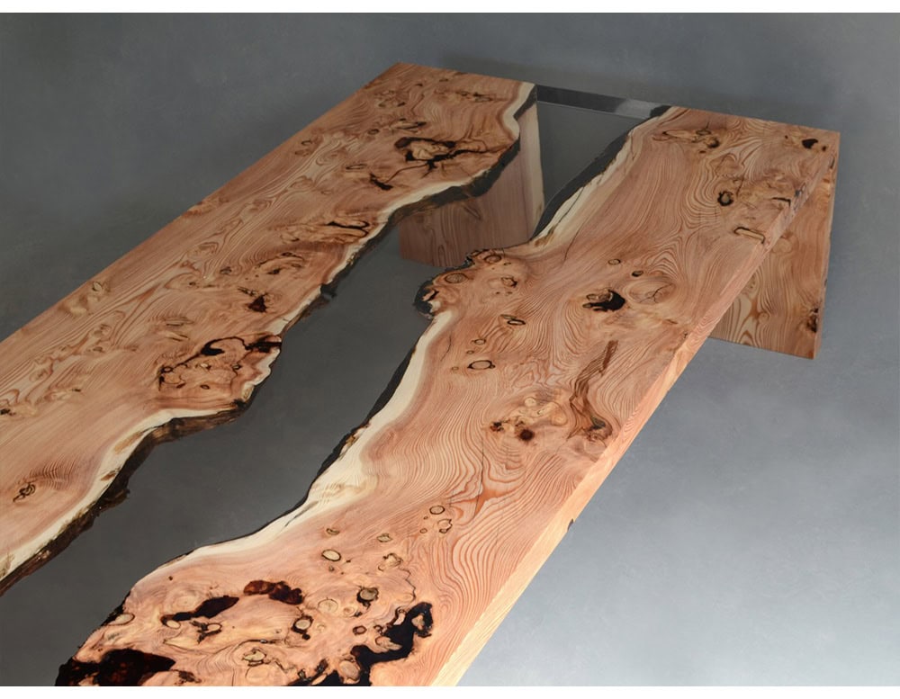 A striking coffee table crafted from natural wood and clear resin, designed to mimic the flowing shapes of a creek. The organic edges and intricate grain patterns contrast beautifully with the smooth resin surface, creating a refined centerpiece.
