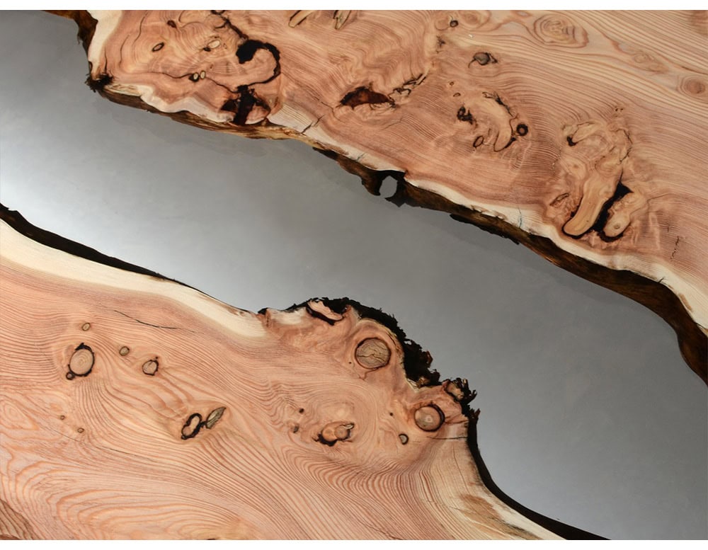 Crafted with natural burl wood and clear resin, this coffee table evokes the flow of water through rugged terrain. Its organic textures and polished surface create a striking, modern centerpiece.