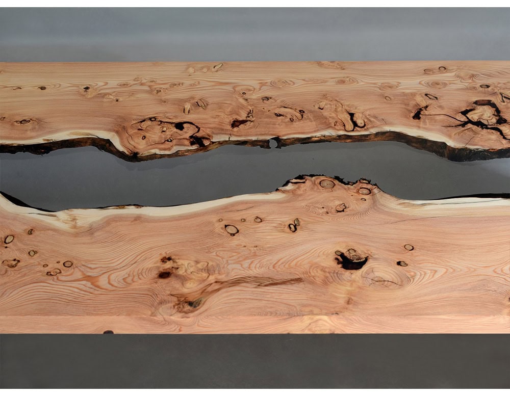 A live edge wood slab flows with resin to form this striking coffee table. The natural knots and grains contrast beautifully with the smooth, glass-like surface.