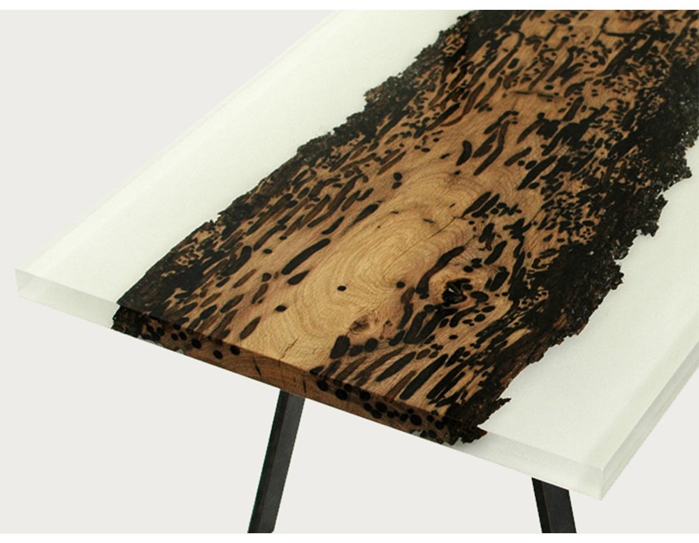 This coffee table features a striking contrast between a foggy white resin surface and a central live-edge wood slab, highlighting the natural textures and patterns of the grain. Its minimal base enhances the bold, contemporary design.