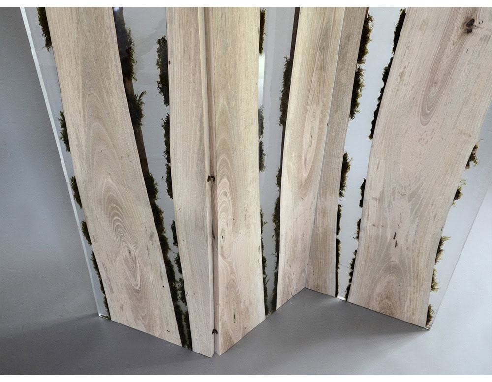 A sculptural screen combining natural wood and moss encased in resin. Its vertical panels create an organic partition with a contemporary feel, balancing raw textures and smooth finishes.