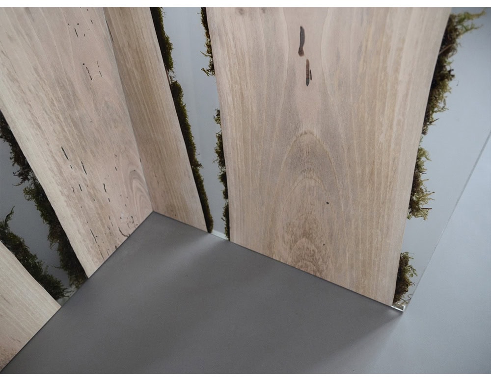 Vertical wood panels with embedded moss bring a natural element indoors. The combination of clean resin surfaces and organic textures creates a sculptural divider with a modern, earthy aesthetic.