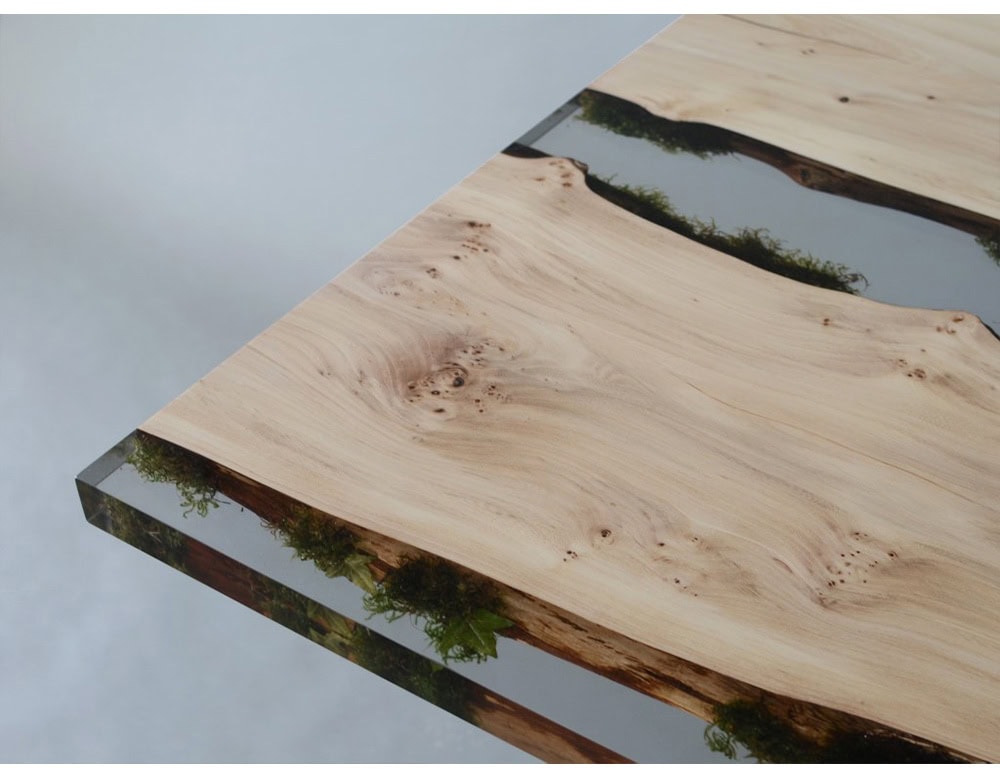 Moss Table blends natural oak slabs with preserved moss embedded in crystal-clear resin, creating a striking river-like effect. Supported by sleek black metal legs, it combines raw nature with modern design for a bold, functional centerpiece.