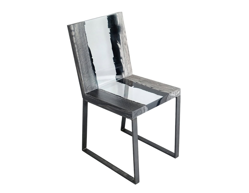 Peatland Chair combines charred wood and clear resin in a sleek frame, highlighting organic patterns within a modern silhouette. The contrast of natural textures and clean lines gives it a sculptural presence.