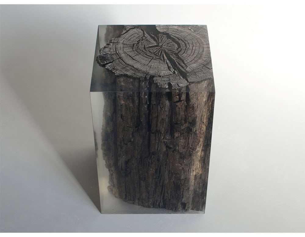 The Peatland Stool encases ancient bog wood in clear resin, creating a striking contrast between natural textures and sleek transparency. Its cube form highlights the preserved grain, making it both functional and sculptural.