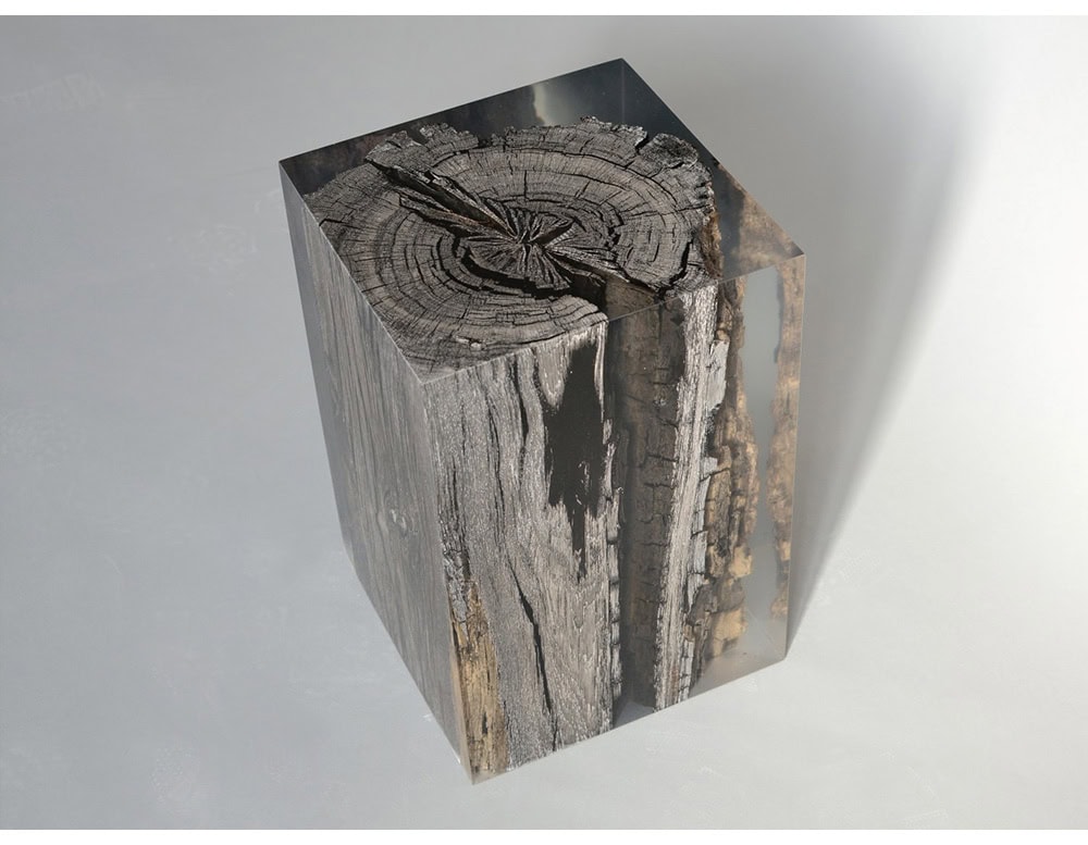 The Peatland Stool combines preserved ancient wood encased in transparent resin, showcasing organic textures with a striking modern form. Its cube-like silhouette highlights natural cracks and grain, merging raw nature with refined design.