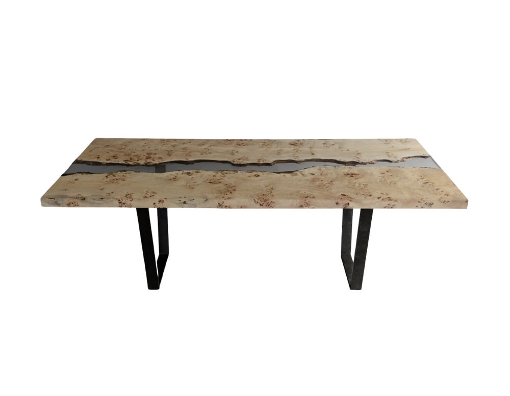 Poplar River Dining Table features two poplar slabs divided by a flowing resin center, evoking the look of water cutting through stone. The natural wood surface rests on sleek metal legs for a modern finish.