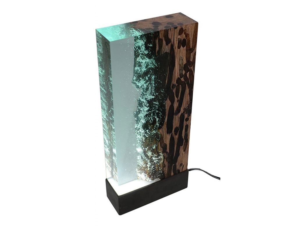 Water Brick Lamp combines rich textured wood with translucent resin that glows when lit. Its rectangular form captures the essence of water and earth in a sculptural lighting piece.