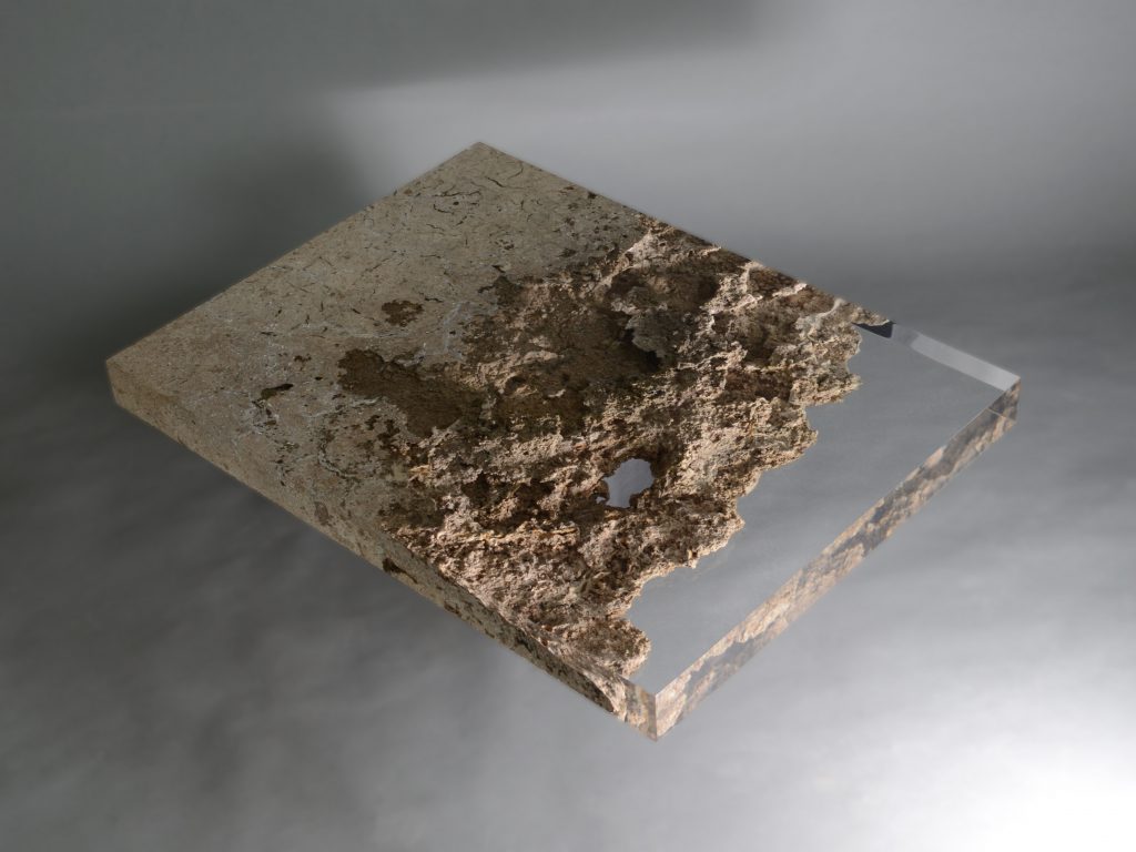 small plate made of natural stone and transparent glass in a brown tone on a gray background