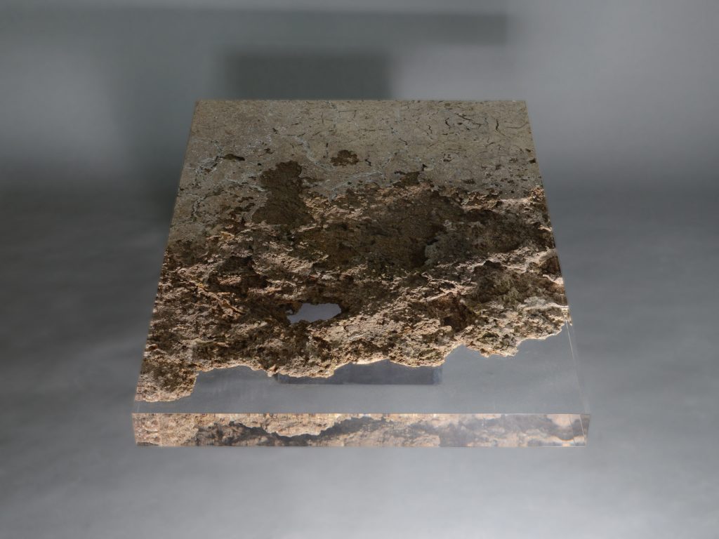 small plate made of natural stone and transparent glass in a brown tone on a gray background