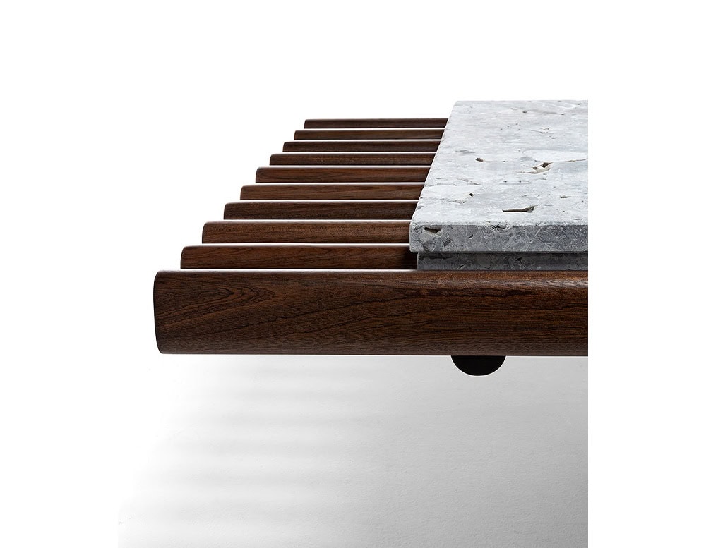 Closeup of Panarea Coffee Table. Upper part made of brown wooden sticks and lower part is a block of yellow stone on a white background.