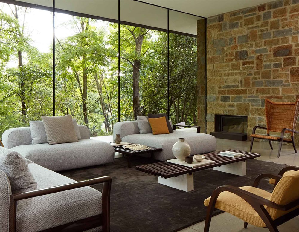 Panarea Coffee Table. Upper part made of brown wooden sticks and lower part is a block of yellow stone in a living room.