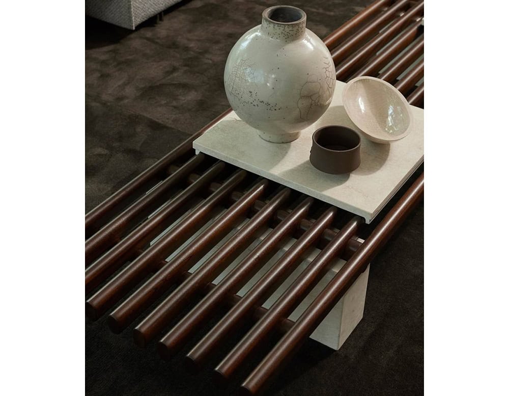 Panarea Coffee Table. Upper part made of brown wooden sticks and lower part is a block of gray stone on a white background.