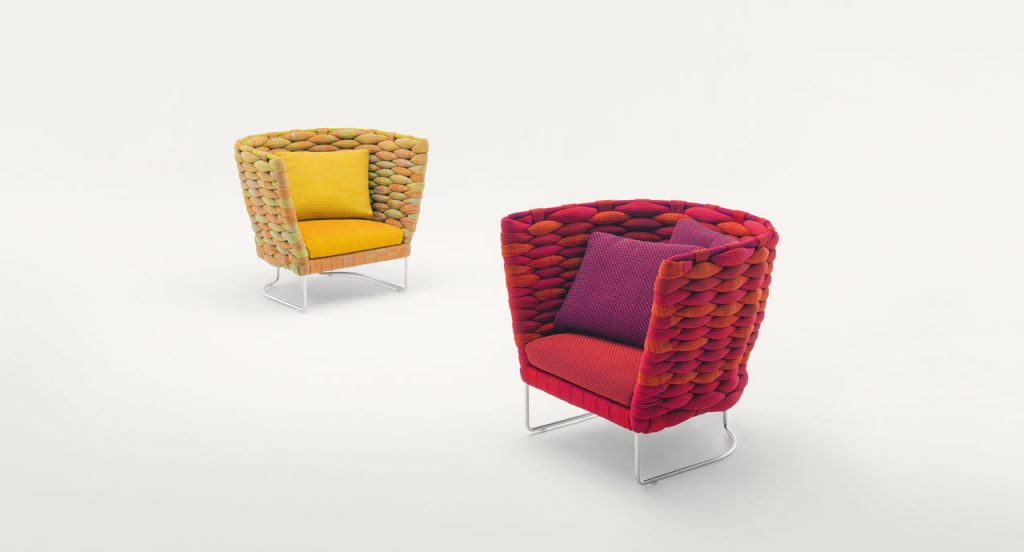 Two Ami Indoor Armchairs, one in red and one in yellow. Structure upholstery of woven fabric, seat cushion of fabric, structure and leg in steel on a white background.