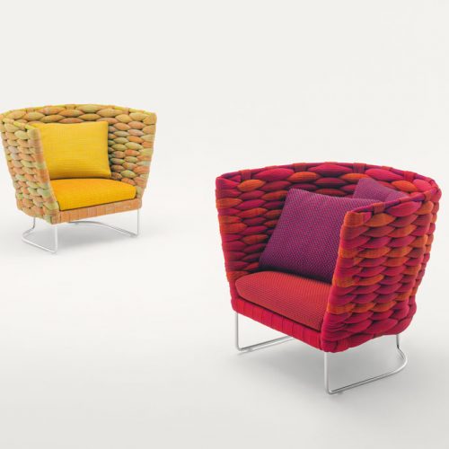 Two Ami Indoor Armchairs, one in red and one in yellow. Structure upholstery of woven fabric, seat cushion of fabric, structure and leg in steel on a white background.