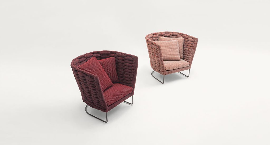 Two Ami Indoor Armchairs, one in red and one in pink. Structure upholstery of woven fabric, seat cushion of fabric, structure and leg in steel on a white background.