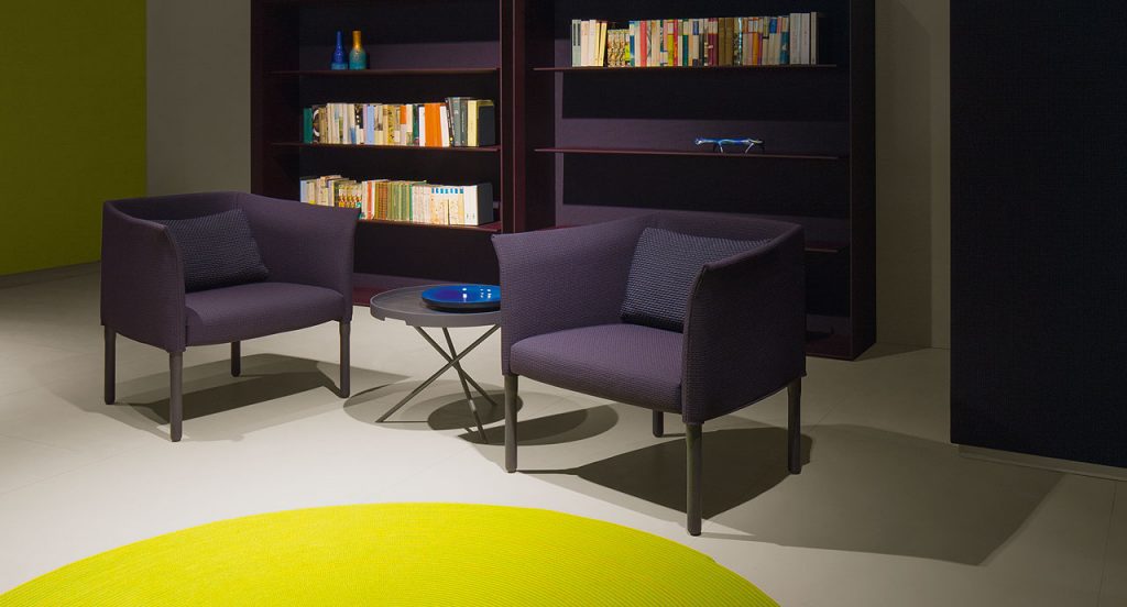 Two Elsie Armchairs, four wooden legs, upholstery in purple in a living room.