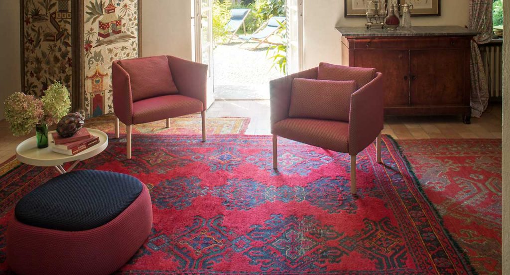 Two Elsie Armchairs, four wooden legs, upholstery in red in a living room.