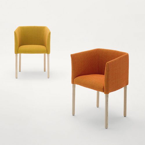 Two Elsie Chairs with armrest, upholstery in fabrics, one in yellow and one in orange, legs in natural heartwood on a white background.
