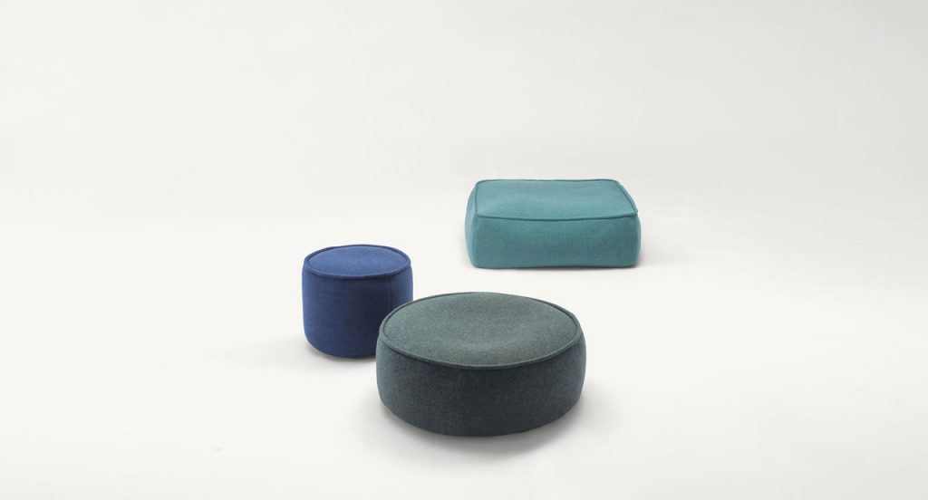 Three Float Indoor Poufs, upholstered in blue fabrics, one square and two round on a white background.