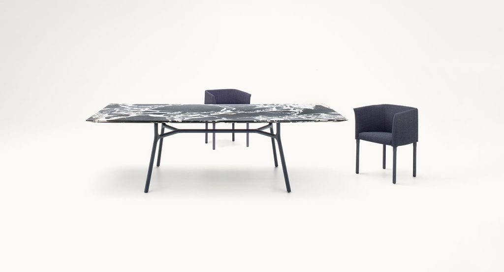 Nesso Indoor Dining Table, white and black wooden top, four legs structure in black aluminium in a dining room.
