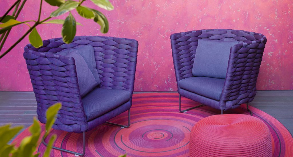 Two purple Ami Outdoor Armchairs, structure upholstery in fabric, seat cushion in fabric, structure and leg in black steel in a living room.