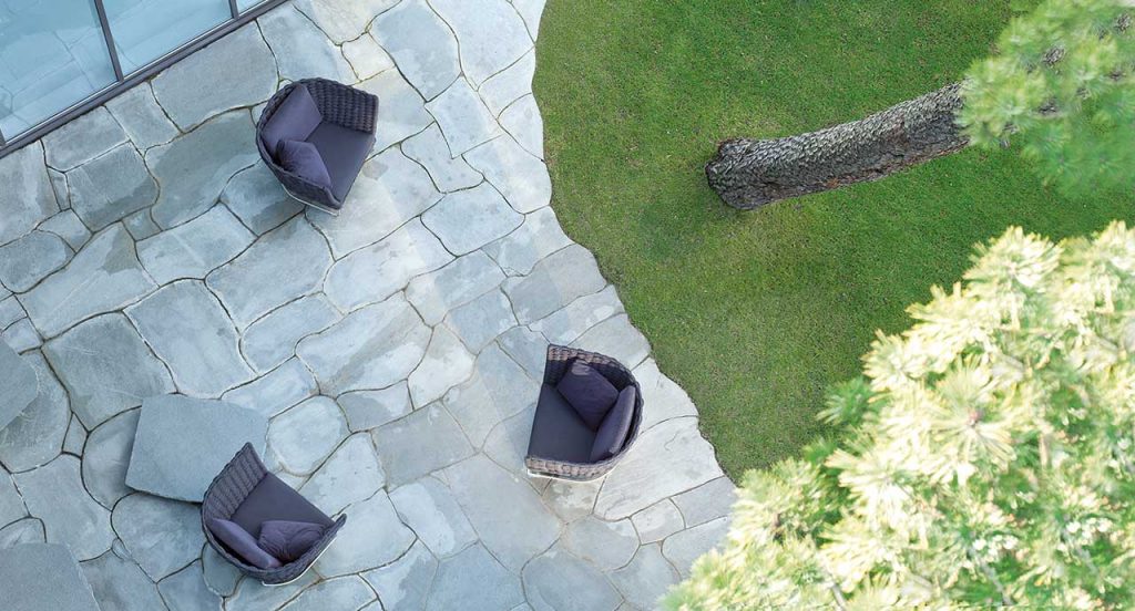 Three gray Ami Outdoor Armchairs, structure upholstery in fabric, seat cushion in fabric, structure and leg in steel in a terrace.