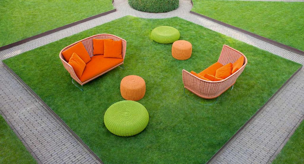 Two Ami Outdoor Sofas, structure and two legs in steel, structure upholstery in orange cord, orange seat cushion in a garden.