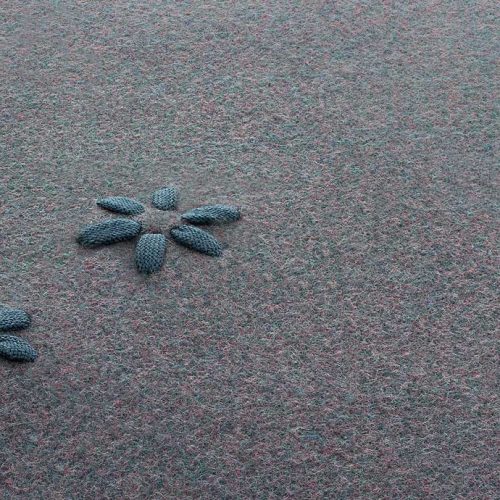 Asterisk rug made of gray felt with a blue floral design made of polyolefin cord.