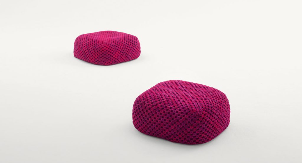 Two Berry poufs made of pink woven upholstery on a white background.