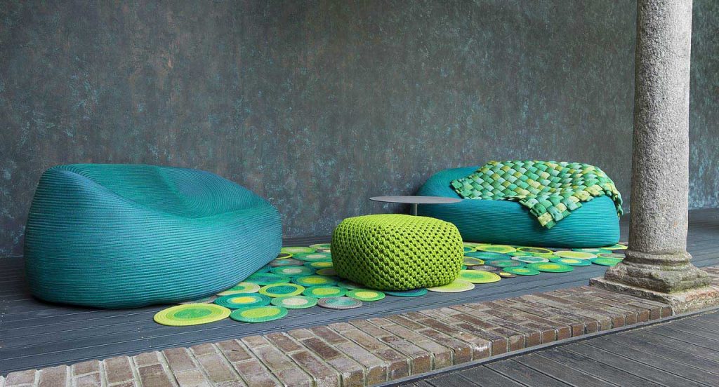 Berry pouf made of green woven upholstery in a terrace.
