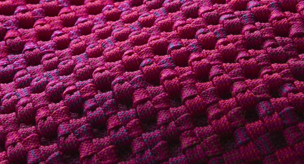 Pink woven upholstery of a Berry pouf.