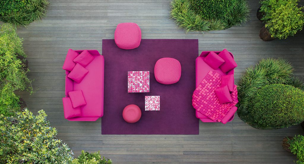 Two Berry poufs made of pink woven upholstery in a terrace.