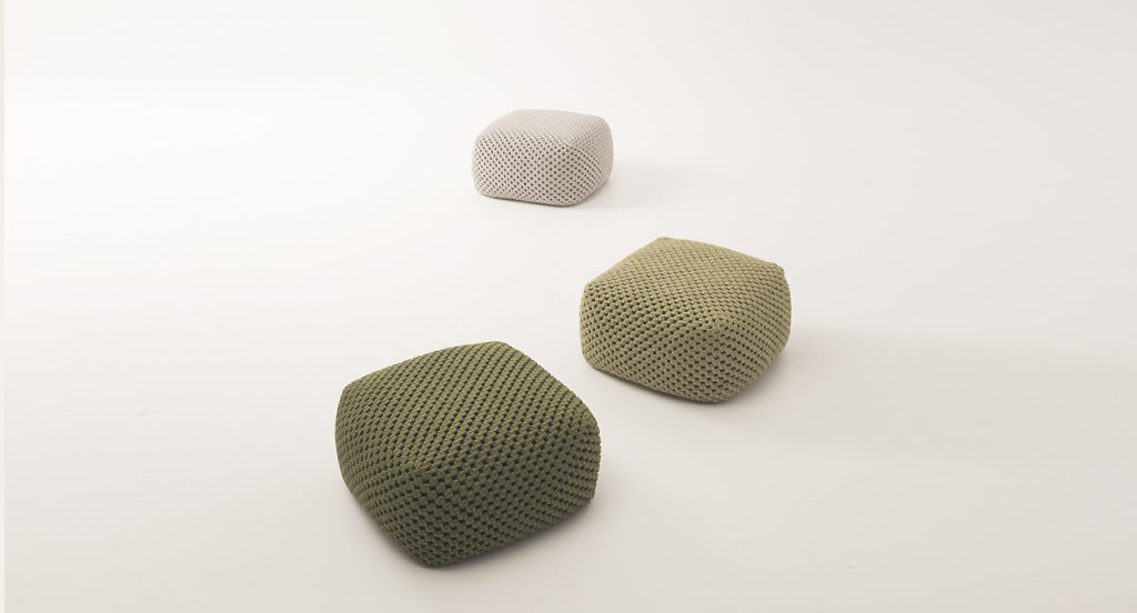 Three Berry poufs made of woven upholstery, one in green, one in beige and one in white on a white background.
