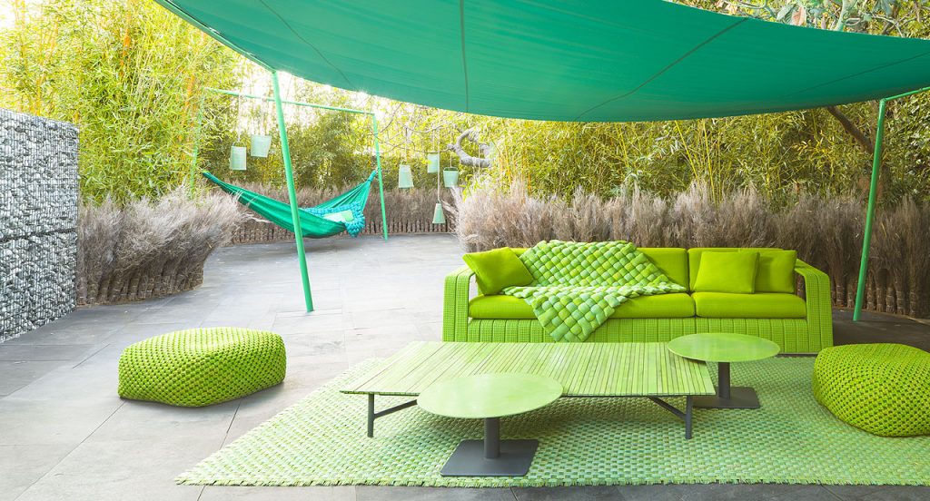 Two Berry poufs made of green woven upholstery in a terrace.