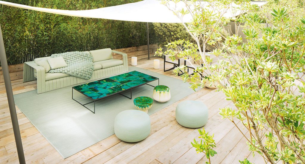 Three beige Calatini side tables with abstract shape, blue and green falling paint pattern in a terrace.