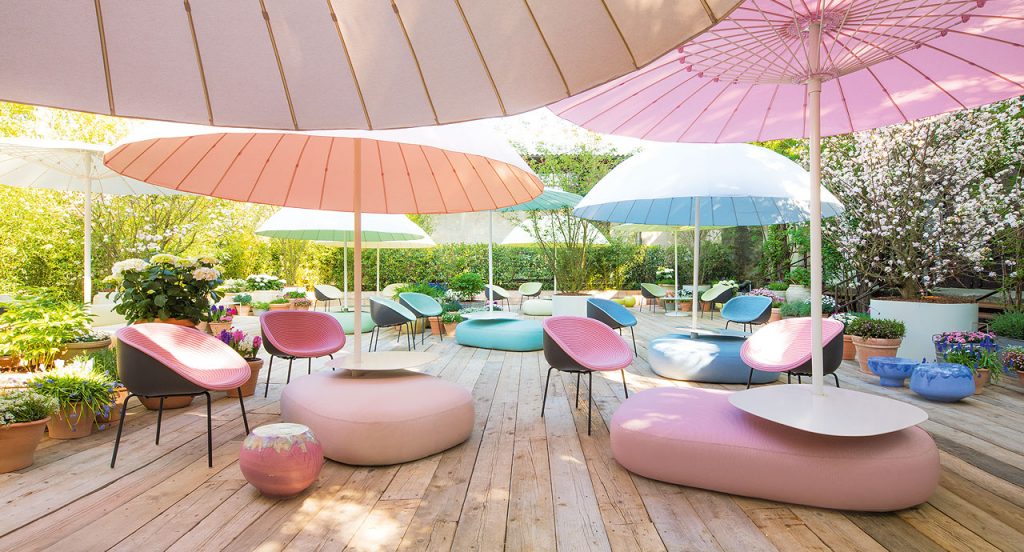 Three Calatini side table with abstract shape, falling paint pattern, two in blue and one in pink and white in a terrace.