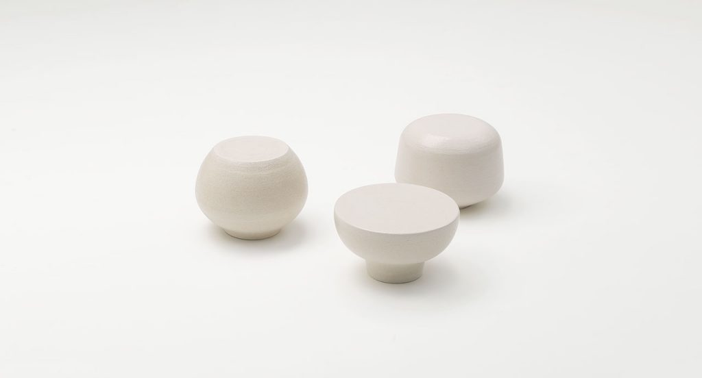 Three white Calatini side tables with abstract shape on a white background.