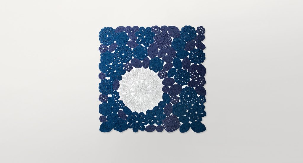 Crochet rug, flowers and leaves made of blue and white rope cord on a white background.