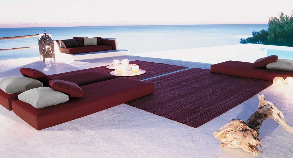 Twelve Outdoor Cushions with upholstery, seven in red and five in white on the beach.